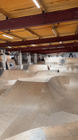Scooter rider performs tricks at indoor skatepark in Corby