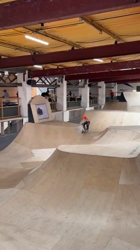Scooter rider performs tricks at indoor skatepark in Corby
