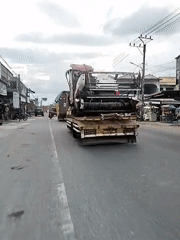 Farm combine transported through Indonesian town on flatbed truck