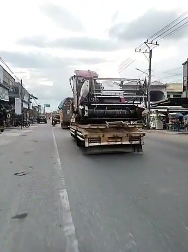 Farm combine transported through Indonesian town on flatbed truck