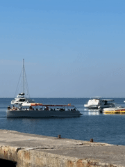 Summer morning on the Budva waterfront: pier, swimmers, and ferry