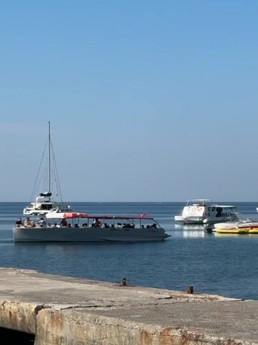 Summer morning on the Budva waterfront: pier, swimmers, and ferry