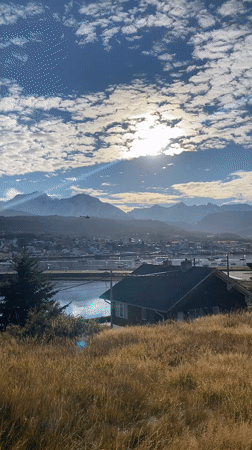 Helicopter flies over Ushuaia bay amid mountain scenery