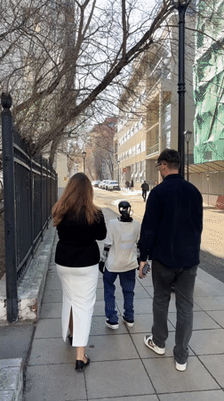 Couple walks with small robot on Moscow sidewalk