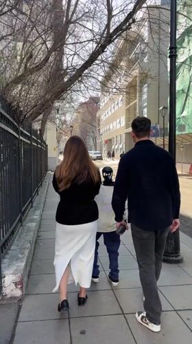 Couple walks with small robot on Moscow sidewalk