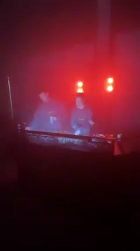 Two DJs perform under colored lighting in Milano venue