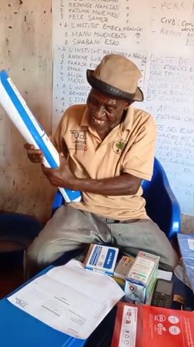 Elderly man conducts paperwork session in Ngalula office