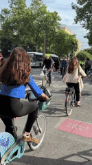 Cyclists navigate Paris street near colorful building art installations