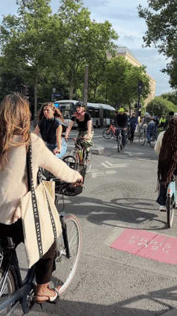 Cyclists navigate Paris street near colorful building art installations