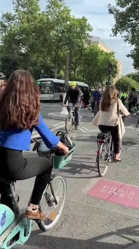 Cyclists navigate Paris street near colorful building art installations