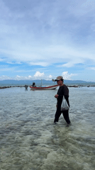 Wading through shallow water near an anchored boat in Thailand
