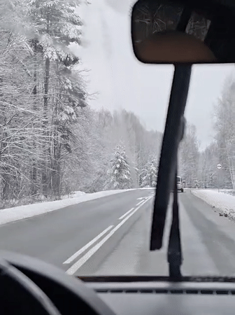 Motorist drives through snowy Russian forest road
