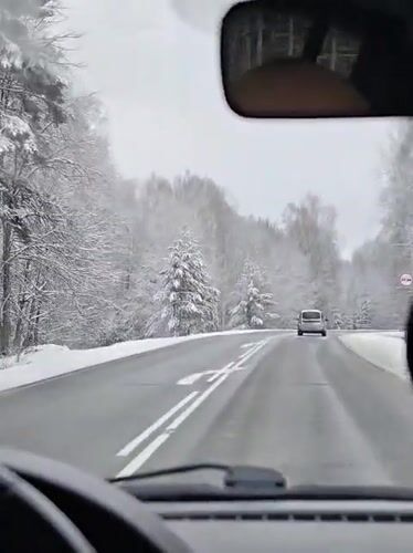 Motorist drives through snowy Russian forest road