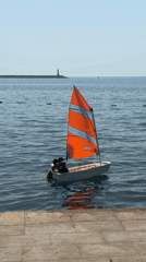 Small sailboat with colorful sail near Bar's stone pier