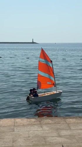 Small sailboat with colorful sail near Bar's stone pier