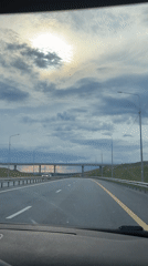 Highway drive under a sun-breaking-through-clouds sky