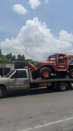 Tow trucks transport multiple off-road vehicles through Tinaquillo streets