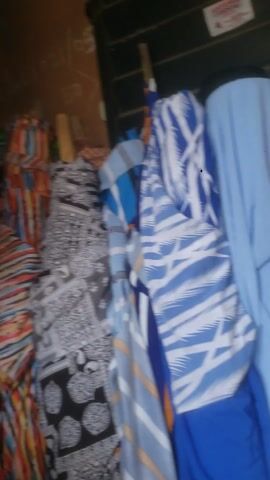 The video shows close-up shots of various fabrics in different colors and patterns. Some fabrics appear to be rolled up, while others are folded or piled. The fabrics include solid colors like red, blue, yellow, and green, as well as patterns like stripes, geometric designs, and floral prints. The camera appears to be moving around, showing the different fabrics from various angles.