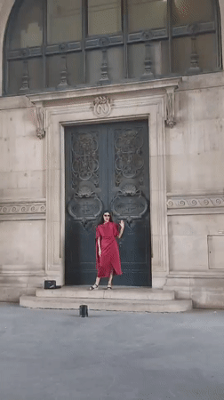 Posing in red at grand ornate doors, waving to camera