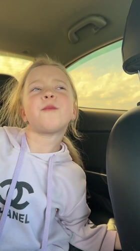Young girl sings along to music in car backseat