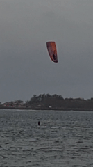Kitesurfers ride choppy Bali waters under stormy skies