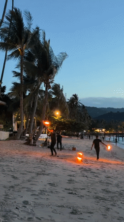 Fire performers light up a Ko Samui beach at dusk