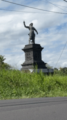 Scooter rider passes statue in Tabanan, Indonesia
