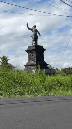Scooter rider passes statue in Tabanan, Indonesia