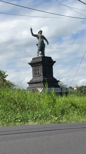 Scooter rider passes statue in Tabanan, Indonesia
