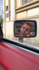 Person takes mirror selfie in red convertible at Belgrade traffic light