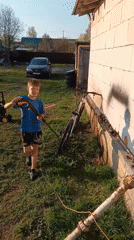 Boy washes bike, German Shepherds play in Andreyevo yard