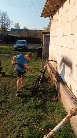 Boy washes bike, German Shepherds play in Andreyevo yard
