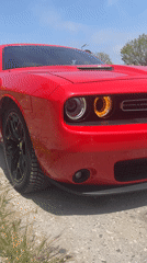 Red Dodge Challenger documented parked on dirt-asphalt surface