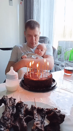 Man holds baby during cake celebration in Andreyevo