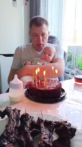 Man holds baby during cake celebration in Andreyevo