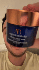Person displays luxury face cream jar in London bedroom