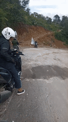 Motorcyclist navigates damaged road in Bintangpermata, Indonesia