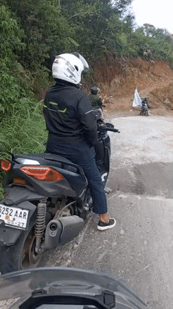 Motorcyclist navigates damaged road in Bintangpermata, Indonesia