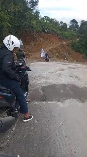 Motorcyclist navigates damaged road in Bintangpermata, Indonesia