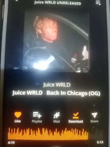 The video shows a smartphone screen displaying the song "Juice WRLD Back In Chicago (OG)" by Juice WRLD. The album art is a picture of Juice WRLD in a car. Below the song title are options to like, add to playlist, mod, download, and share the song. An equalizer graphic shows the audio waveform. The song duration is 5:13, and the current playback time is 0:00. The phone appears to be in a dark environment, possibly a car at night, based on reflections and the lighting.
