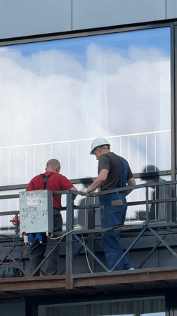 Construction workers perform scaffold work near building window