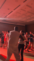 Diverse group dances under red lighting in large room