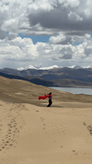 Person plays with red fabric across sand dunes in Labrang