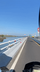 Motorcycle crosses bridge with guardrails in Kuta, Indonesia