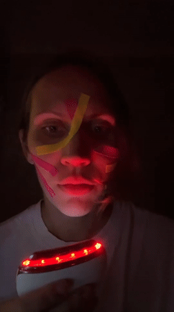 Person applies glowing kinesiology tape in geometric face patterns