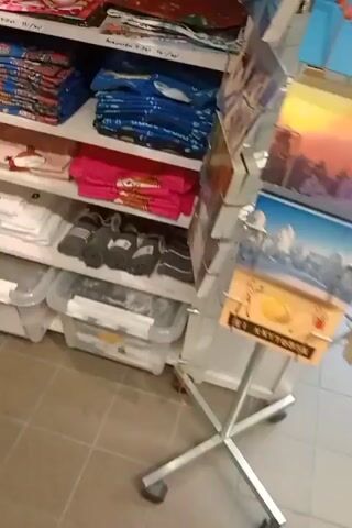 The video shows shelves of children's clothing and accessories in a retail store. The shelves are stocked with items such as onesies, hats, sweaters, and bibs. Some items are folded neatly, while others are displayed on hangers or in bins. There are also some stuffed animals and other decorative items on the shelves. The store appears to be well-organized and brightly lit. The video is filmed from a handheld perspective, and the camera is shaky at times.