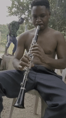 Street musician plays clarinet outdoors in Mararaba, Nigeria