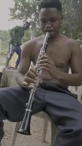 Street musician plays clarinet outdoors in Mararaba, Nigeria