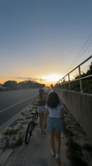 Two women walk with bicycle at Panama City Beach
