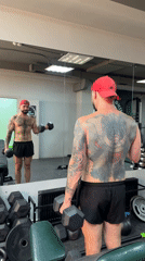 Dumbbell curls in a Voronezh gym, mirror reflection in frame.